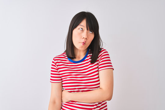 Young beautiful chinese woman wearing red striped t-shirt over isolated white background making fish face with lips, crazy and comical gesture. Funny expression.