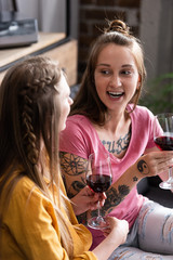 two lesbians holding wine glasses while sitting on sofa in living room