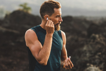 Man using wireless earphones air pods on running outdoors. Active lifestyle concept. - 279940319