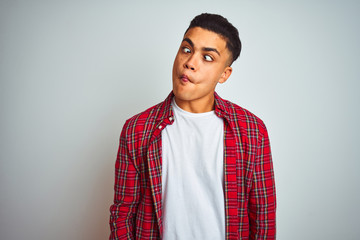 Young brazilian man wearing red shirt standing over isolated white background making fish face with lips, crazy and comical gesture. Funny expression.