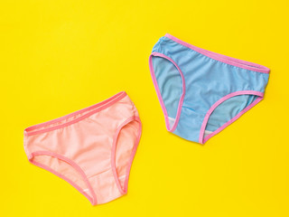 Blue and pink panties on a light yellow background. The concept of meeting lovers. Underwear. The view from the top.