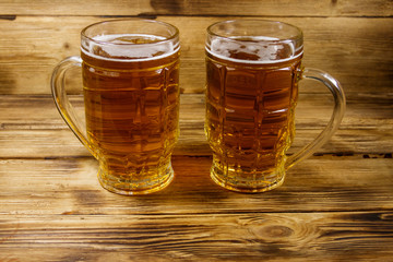 Two mugs of beer on a wooden table