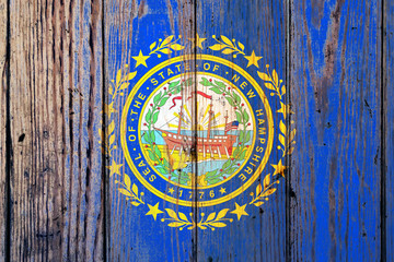 Fototapeta na wymiar New Hampshire US state national flag on a gray wooden boards background on the day of independence in different colors of blue red and yellow. Political and religious disputes, customs and delivery.