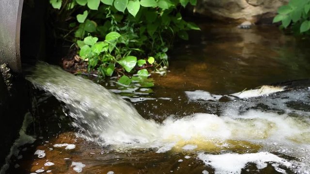 Dirty water flows from a pipe in river, environmental pollution.