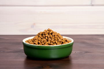 bowl full of dry pet food on wooden background. space for your text