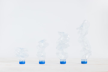 Garbage recycle plastic bottles on white wooden board setting  from low to high, Global warming solution, Environment concept