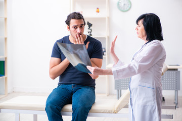 Fototapeta premium Young male patient visiting aged female doctor