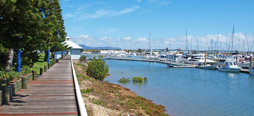 Obraz premium Tropical timber waterfront marina board walk with boats.