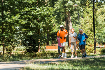 selective focus multicultural senior men and women in sportswear jogging in park