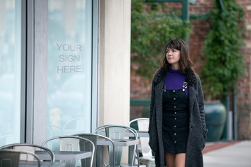 Woman walking outdoors in the city looking at text or logo space on a window display.  Advertising...