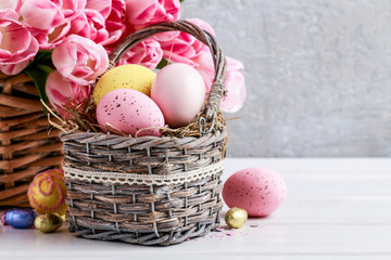Bouquet of pink tulips and basket of Easter eggs