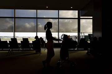 Silhouettes of women with luggage carts in airport departure lounge