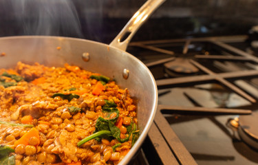 A healthy home cooked meal of lentils with spinach sausage and carrots cooking on a gass stove.