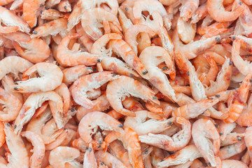 Pink fresh frozen shrimps with ice in a supermarket or fish shop. Uncooked seafood close up background. Fresh frozen prawns, delicacies, sea food concept,
