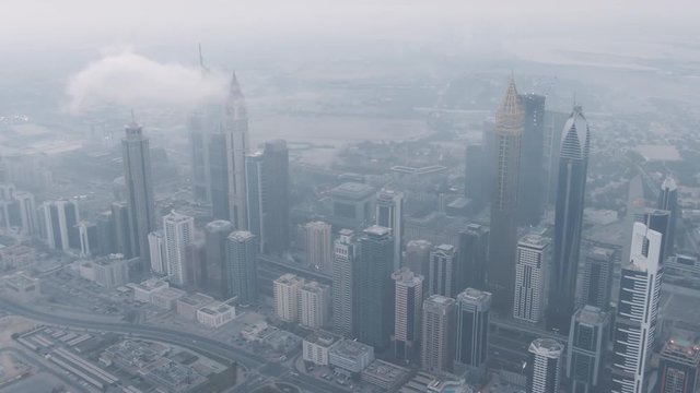 Aerial Drone Footage of the famous Financial District of Dubai, United Arab Emirates along the sheikh zayed road while sunrise with many skyscrapers and the skyline of dubai
