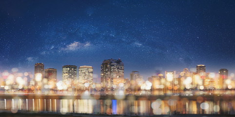 Abstract city at night with Bokeh light background. Panoramic modern building at night with glowing light and starry sky © SasinParaksa