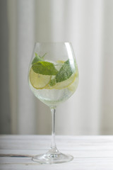 Refreshing mojito cocktail with lime and mint in a tall glass on a light background