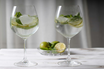 Refreshing mojito cocktail with lime and mint in a tall glass on a light background