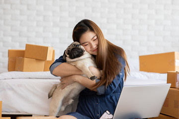 SME entrepreneur of Young women working with laptop for Online shopping at home with her dog pug breed,Cheerful and Happy with box for packaging in home,Own Business Start up and Freelance concept