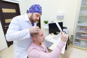 Baldness treatment. Patient suffering from hair loss in consultation with a doctor. Preparation for hair transplant surgery. The line marking the growth of hair. The patient controls the marking in