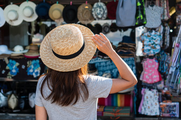 Women hold the hat and look at the souvenir shop