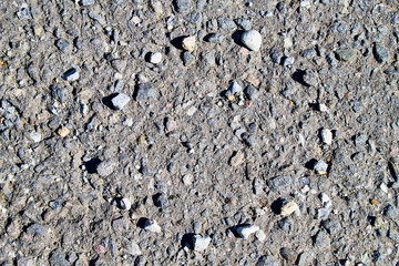 Stone asphalt texture of road and pebbles circle. Grey asphalt road and and a hand-made circle of gravel. Background pebble and gravel