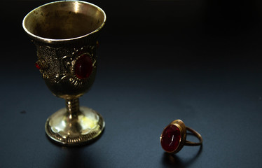 Fototapeta na wymiar Silver cup and ring with red rubin, antiques on black background