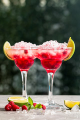 margarita cocktail with lime and raspberries on nature background