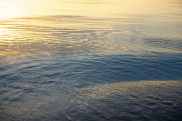 Colorful yellow and blue water surface with ripples on the sea.