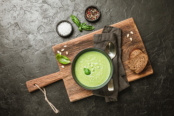 Broccoli cream soup in black plate over dark stone background, top view