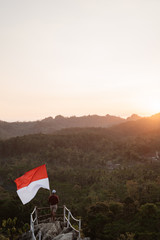 portrait of man on top of the hill in the morning rising indonesian flag celebrating independence day