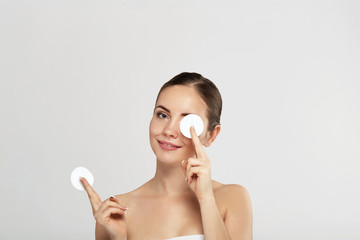 Obraz na płótnie Canvas Woman Cleaning Face With White Pad. Beautiful Girl Removing Makeup White Cosmetic Cotton Pad. Happy Smiling Female Taking Off Makeup From Facial Skin With Cosmetic Pad. Face Skin Care.