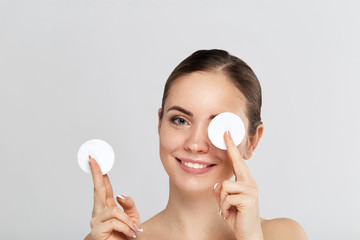 Beauty portrait of a cheerful young topless woman removing face make-up with a cotton pad