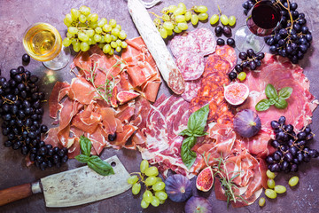 Different types jamon on cutting boardes with figs, grapes and wine. Parma ham, hamon on wooden...