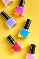 Color nail polish bottles on yellow background composition.