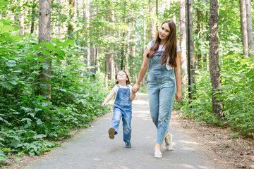 Obraz premium Family, children and nature concept - Portrait of attractive woman and little child girl walking together