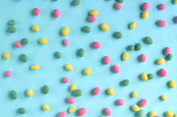 Colored sweets, peanut covered with glaze on blue background composition.