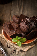 Homemade delicious chocolate muffins with mint and chocolate on wooden background close-up