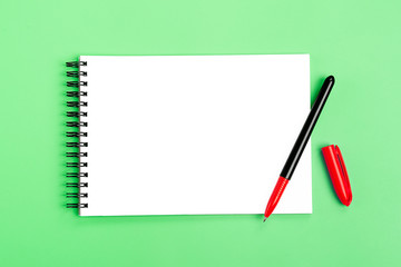 school notebook and red pen on green light background, spiral notepad on a table Top view Flat lay