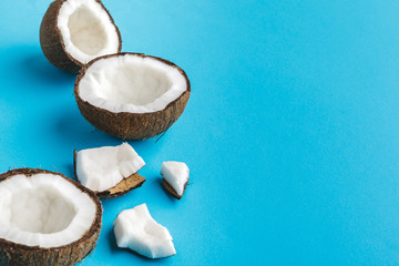 Slices of broken tropical coconuts on blue background. Top view