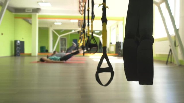 The trainer teaches in the gym to practice a man on the hinges of the TRX while performing an exercise facial thrust, group lesson, workout
