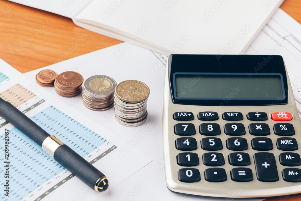 Wall mural pile of money coins with graph paper on wood table, concept in account, finance and growth of business