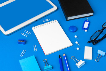 Flat lay, top view of blue office table desk. Workspace with blank note book,  office supplies