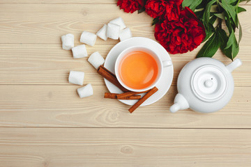 Cup of green tea on table with fresh peony flowers