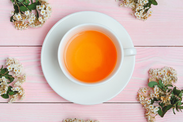 Green tea in a ceramic cup with branches of blossoming tree branches