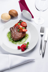 beef stake with strawberry on white dish and basil saus