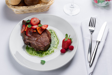 beef stake with strawberry on white dish and basil saus