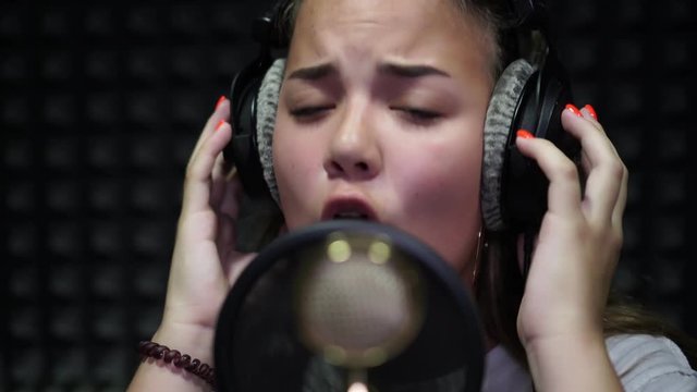 Vocal recording studio. Portrait of a girl who sings into a microphone.