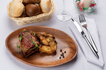 fried beef stake with potatoes and sprouted peas on a white table