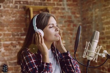 Woman in headphones recording music video blog home lesson, singing or making broadcast internet...